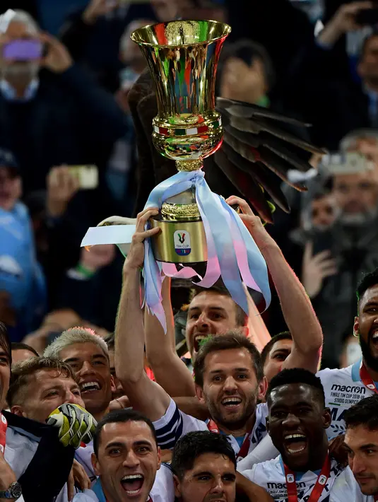 Gelandang Lazio, Senad Lulic memegang trofi Coppa Italia saat merayakan kemenangan timnya atas Atlanta pada akhir babak final di Stadio Olimpico, Roma, Rabu (15/5/2019). Lazio keluar sebagai juara Coppa Italia setelah mengalahkan Atalanta 2-0. (Vincenzo PINTO / AFP)