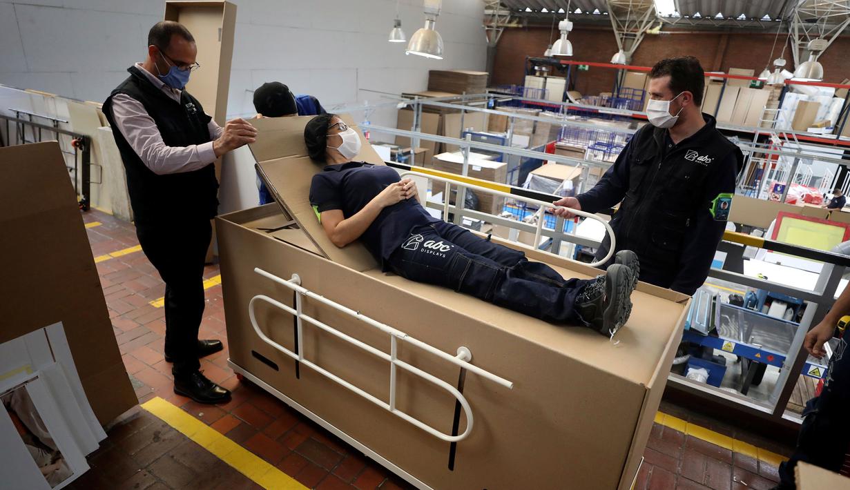 Rodolfo Gomez dan karyawannya mendemonstrasikan desain kardus mereka dapat berfungsi sebagai tempat tidur rumah sakit dan peti mati untuk pasien COVID-19 di Bogota, Kolombia, Jumat (8/5/2020). Perusahaan ini menanggapi kekurangan tempat tidur dan peti mati selama pandemi.  (AP/Fernando Vergara)