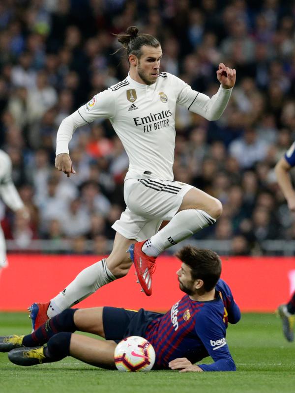 Gelandang Real Madrid, Gareth Bale berusaha melewati gelandang Barcelona, Gerard Pique selama pertandingan lanjutan La Liga Spanyol di stadion Santiago Bernabeu, Madrid (2/3). Barcelona menang tipis atas Real Madrid 1-0. (AP Photo/Andrea Comas)