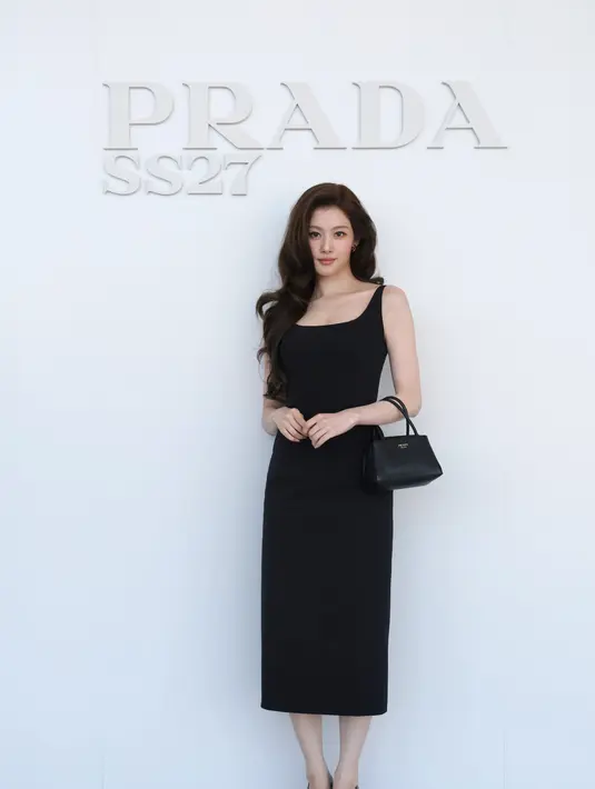 Sana tampil dengan dress midi hitam berleher persegi, dilengkapi tas tote Prada hitam dan pumps hitam, rambut ditata bergelombang [dok. Prada]