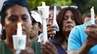Seorang wanita berdoa sambil memegang lilin  saat menghadiri acara untuk korban penembakan brutal di festival kuliner Gilroy Garlic di Gilroy, California (29/7/2019). Tiga orang tewas dan sedikitnya puluhan orang terluka akibat kejadian tersebut. (AFP Photo/Mario Tama)