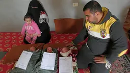 Pasangan Nidal dan Islam Al-Saiqli berpose dengan bayi kembar mereka, Jerusalem, Capital dan Palestine di Khan Yunis, Jalur Gaza, Jumat (2/2). Pasangan Nidal dan Islam memberi nama unik kepada tiga bayi kembar mereka yang baru lahir. (SAID KHATIB/AFP)