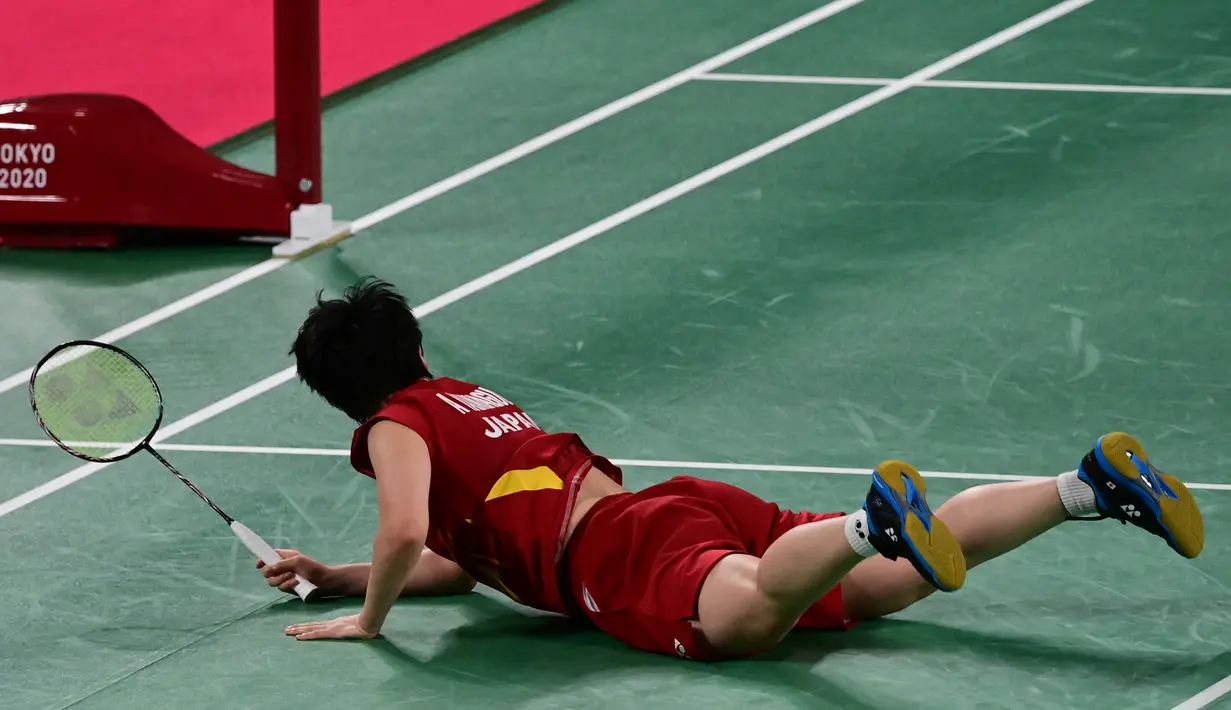 Akane Yamaguchi dari Jepang jatuh di lapangan saat mengembalikan kok ke pemain Korea Selatan Kim Ga-eun dalam pertandingan babak 16 besar bulu tangkis tunggal putri Olimpiade Tokyo 2020 di Musashino Forest Sports Plaza di Tokyo pada 29 Juli 2021. (Pedro PARDO / AFP)