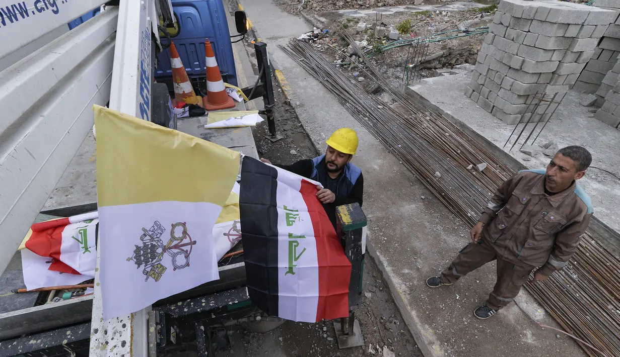 Pekerja mengibarkan bendera Irak dan Takhta Suci Vatikan di tiang-tiang jalan di kota Mosul, Irak, Kamis (4/3/2021). Pemimpin Tertinggi Umat Katolik Paus Fransiskus memulai kunjungan bersejarah ke Irak pada Jumat (5/3), meskipun menghadapi pandemi Covid-19 dan ancaman keamanan. (Zaid AL-OBEIDI/AFP)