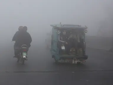 Becak dan pengendara sepeda motor melaju di jalan saat kabut tebal mengurangi jarak pandang di Lahore, Pakistan, Selasa (30/11/2021). Lahore secara konsisten menempati peringkat sebagai salah satu kota terburuk di dunia untuk polusi udara. (AP Photo/K.M. Chaudary)