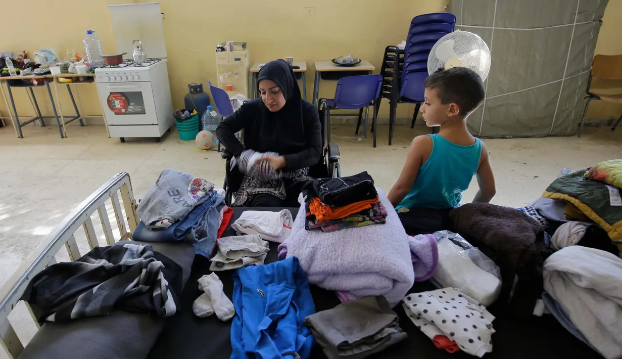 Seorang wanita Lebanon yang mengungsi melipat pakaian di dalam ruang kelas di sebuah sekolah yang menampung para pengungsi Lebanon, di kota Deir Ammar, Lebanon utara, pada 17 Oktober 2024. (Ibrahim Chalhoub/AFP)