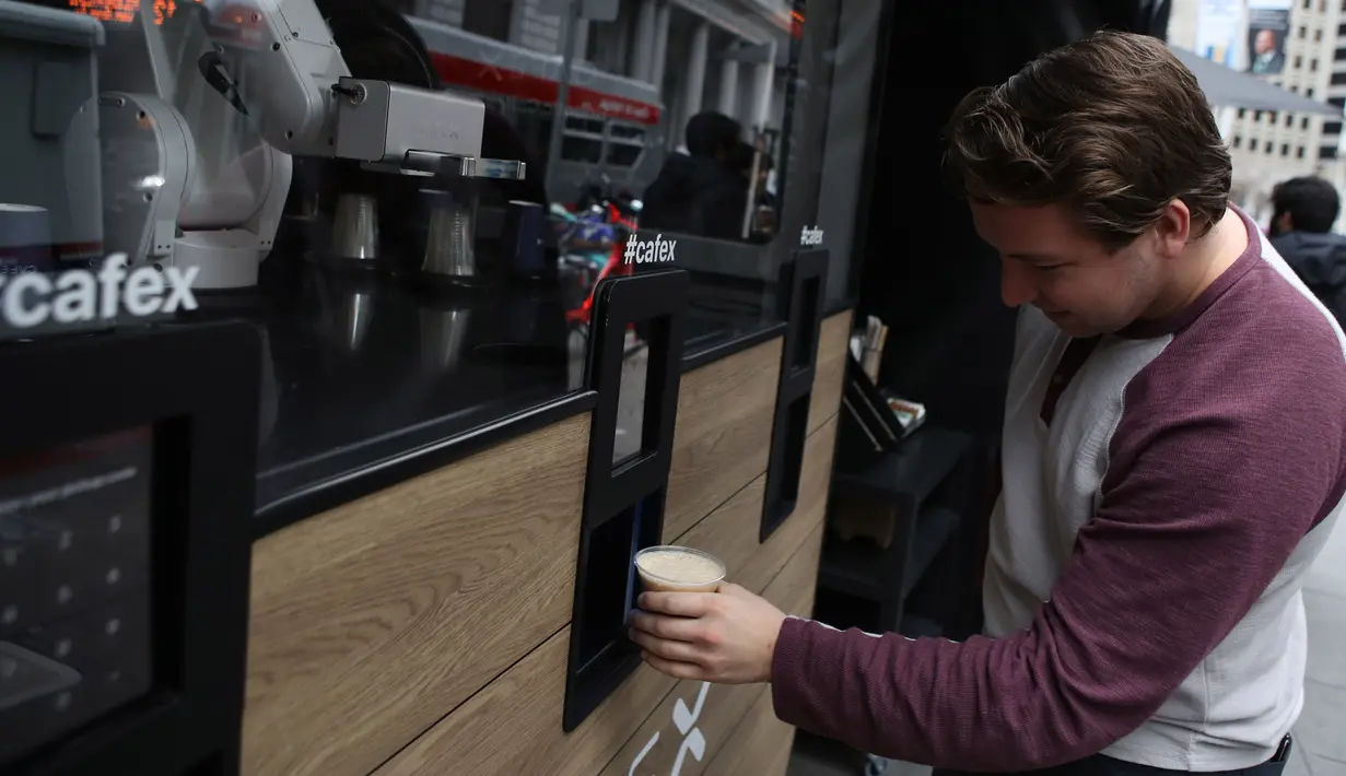 Pelanggan mengambil kopi yang dibuat oleh robot barista di Cafe X, San Francisco, California, AS, Selasa (12/2). Warga San Francisco sudah bisa menerima kopi buatan robot yang dinilai layak, cepat, DAN menyenangkan. (Justin Sullivan/Getty Images/AFP)
