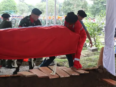 Sejumlah personel TNI menurunkan peti jenazah Zumarnis Zein, ayah artis Marini Zumarnis ke liang lahat di TPU Karet Bivak, Jakarta, Jumat (17/6). Prosesi pemakaman dilakukan secara militer, diiringi bunyi tembakan. (Liputan6.com/Herman Zakharia)