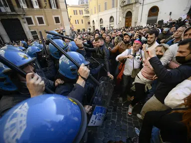 Polisi anti huru-hara (kiri) menggunakan tongkat untuk melawan pengunjuk rasa saat bentrokan dalam aksi protes oleh pemilik restoran dan aktivitas bisnis lainnya di luar parlemen di Piazza Montecitorio di Roma, Selasa (6/4/202). Mereka menuntut untuk membuka kembali bisnis. (Filippo MONTEFORTE/AFP)