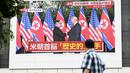 Pejalan kaki melihat layar yang menampilkan pertemuan antara pemimpin Korea Utara Kim Jong-un dan Presiden AS Donald Trump di Tokyo, Selasa (12/6). Untuk pertama kalinya dalam sejarah, Donald Trump dan Kim Jong-un bertemu. (AFP PHOTO/Martin BUREAU)