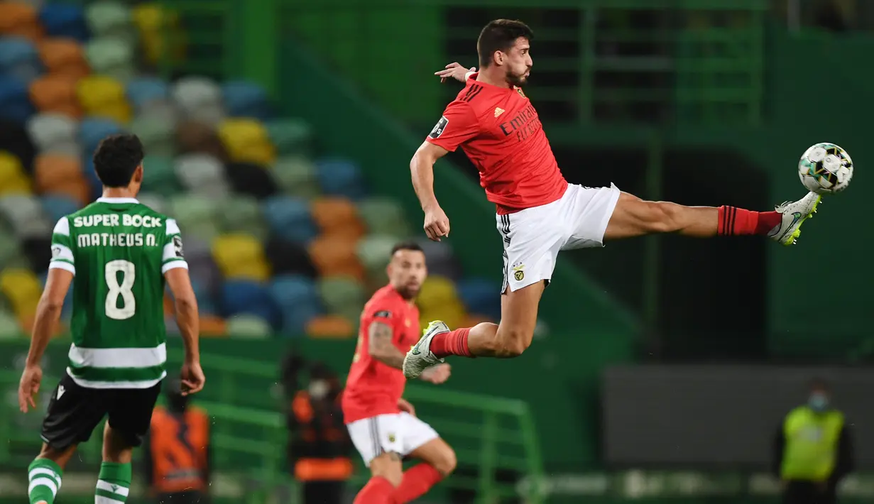 Gelandang Benfica, Gabriel (kanan) menendang bola sambil melompat dalam laga lanjutan Liga Portugal 2020/21 melawan Sporting Lisbon di Jose Avalade Stadium, Lisbon, Senin (1/2/20201). Benfica kalah 0-1 dari Sporting. (AFP/Patricia De Melo Moreira)