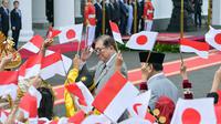 Kedatangan PM Shigeru Ishiba lalu disambut murid sekolah yang mengibarkan bendera Indonesia dan Jepang sambil mengucapkan kalimat selamat datang dalam bahasa Jepang. (Bay ISMOYO/AFP)