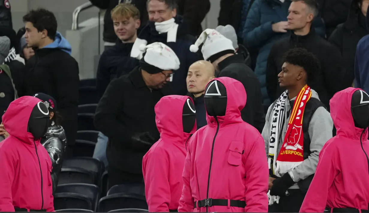 Orang-orang berpakaian seperti penjaga Squid Games dengan berdiri di area penonton selama pertandingan lanjutan Liga Inggris 2024/2025 antara Tottenham Hotspur melawan Liverpool di Stadion Tottenham Hotspur, London, Inggris Minggu (22/12/2024). Seperti diketahui, aksi tersebut ternyata merupakan promo musim kedua serial Korea Selatan tersebut. (AP Photo/Dave Shopland)