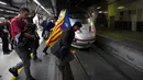Pengunjuk rasa membawa bendera Catalonia melompat ke jalur kereta api di Stasiun Sants di Barcelona (8/11). Pengunjuk rasa memblokir jalan dan jalur kereta api setelah para pemimpin separatis ditahan di Madrid. (AFP Photo/Lluis Gene)