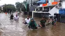 Warga melintasi banjir yang merendam Benhil, Jakarta, Selasa (25/2/2020). Hujan yang mengguyur wilayah tersebut membuat air sungai meluap sehingga menyebabkan Banjir setinggi pinggang orang dewasa. (Liputan6.com/Angga Yuniar)