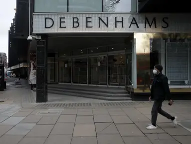 Seorang pria yang mengenakan masker berjalan melewati papan informasi virus corona di sebelah department store andalan Debenhams yang ditutup di Oxford Street di London, Sabtu (6/2/2021). Debenhams, yang berusia 242 tahun, menyatakan mereka dalam proses penutupan massal. (AP Photo/Matt Dunham)