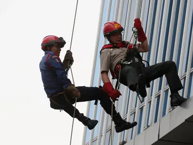 Kepala BNPB Willem Rampangilei (kanan) dievakuasi menggunakan tali dari lantai 10 saat simulasi bencana di Gedung Graha BNPB, Jakarta, Kamis (26/4). Simulasi dilakukan dalam rangka Hari Kesiapsiagaan Bencana Nasional. (Liputan6.com/Arya Manggala)
