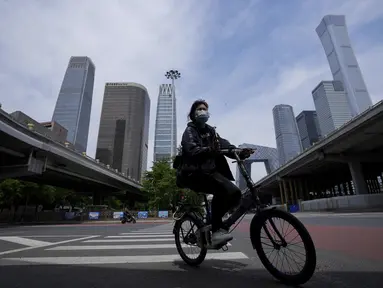 Seorang perempuan mengenakan masker berkendara melintasi persimpangan yang tenang di kawasan pusat bisnis saat perintah bekerja dari rumah di distrik Chaoyang, Beijing, Rabu (11/5/2022). Shanghai pada Rabu menegaskan kembali akan mempertahankan pendekatan &ldquo;nol-COVID&rdquo; pengendalian pandemi, sehari setelah kepala Organisasi Kesehatan Dunia (WHO) menyatakan kebijakan itu tidak berkelanjutan dan mendesak China mengubah strategi. (AP Photo/Andy Wong)