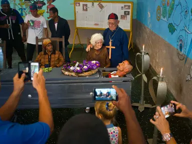 Pria bernama Divaldo Aguiar berbaring di dalam peti saat melakukan festival Burial of Pachencho di Santiago de Las Vegas, Kuba (5/2). Perayaan ini merupakan tardisi masyarakat setempat yang digelar setiap tangggal 5 Februari. (AP Photo/Ramon Espinosa)