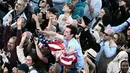 Robert Francis Prevost yang lahir di Chicago pada 1955 merupakan Paus pertama yang berasal dari Amerika Serikat. Tampak dalam foto, seorang pria melambaikan bendera AS di Lapangan Santo Petrus saat paus yang baru terpilih diumumkan di Vatikan, pada 8 Mei 2025. (Filippo MONTEFORTE/AFP)