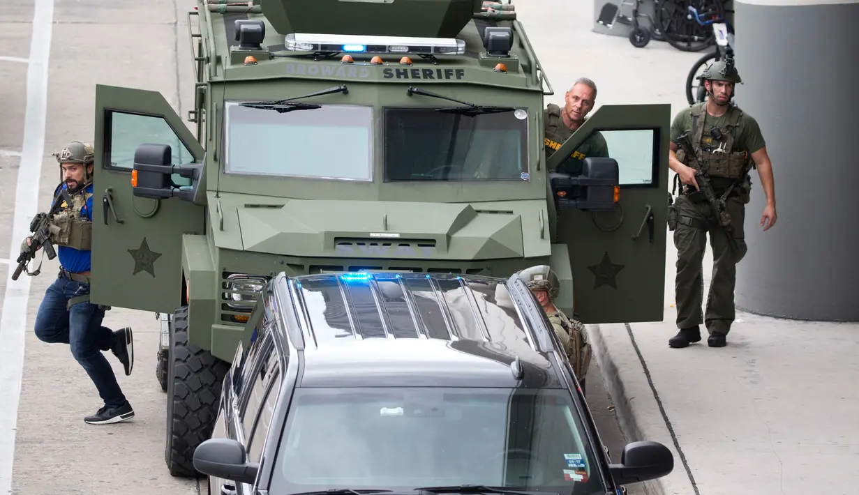 Sejumlah petugas kepolisian turun dari kendaraan militer saat terjadi penembakan di Bandara Fort Lauderdale, Florida, AS (6/1). Diketahui pelaku penembakan pernah bertugas di Irak selama setahun. (David Santiago/El Nuevo Herald via AP)