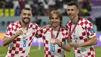 Tiga pemain Kroasia, Luka Modric (tengah), Mateo Kovacic (kiri), dan Ivan Perisic berpose dengan medali setelah meraih peringkat ketiga di Piala Dunia 2022. Ini merupakan kedua kalinya Kroasia meraih peringkat ketiga dalam perhelatan akbar empat tahunan ini, sebelumnya pada Piala Dunia 1998 Kroasia langsung menjadi tim peringkat ketiga dalam debut mereka di Piala Dunia. (AP Photo/Frank Augstein)