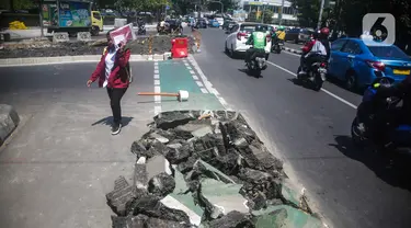 Pejalan kaki melintas di samping jalur sepeda yang di bongkar di kawasan Cikini, Jakarta, Selasa (19/11/2019). Jalur sepeda berumur 2 bulan tersebut dibongkar akibat proyek pelebaran trotoar. (Liputan6.com/Faizal Fanani)