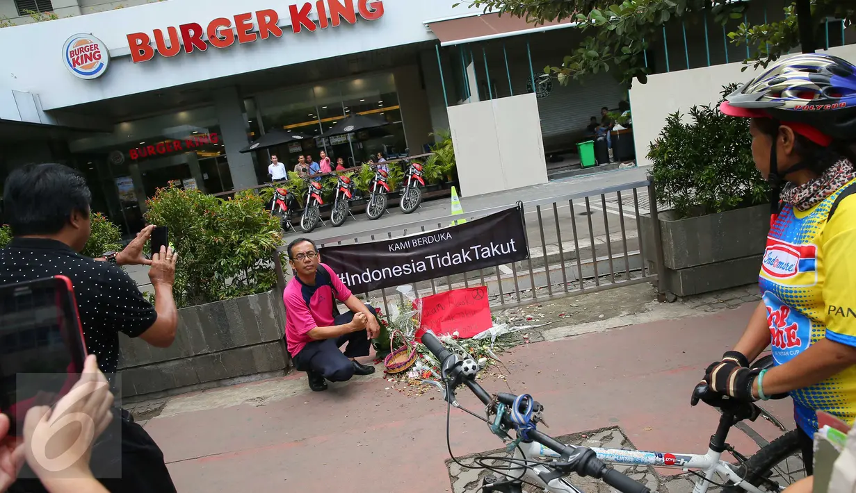 Warga berfoto di dekat poster #Indonesiatidaktakut yang dipasang di depan Menara Cakrawala, Jakarta, Sabtu (16/1). Lokasi teror di kawasan Sarinah Thamrin terus didatangi warga untuk mengabadikan diri atau foto selfie. (Liputan6.com/Faizal Fanani)