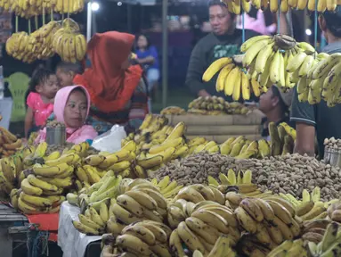 Pedagang menjual pisang dan kacang di pasar malam pada tradisi Malam Qunut di Desa Payunga, Kec. Batudaa, Kab. Gorontalo, Senin (20/5/2019). Tradisi Malam Qunut di Gorontalo dilakukan pada setiap pertengahan bulan Ramadan dengan beramai-ramai memakan pisang dan kacang. (Liputan6.com/Arfandi Ibrahim)