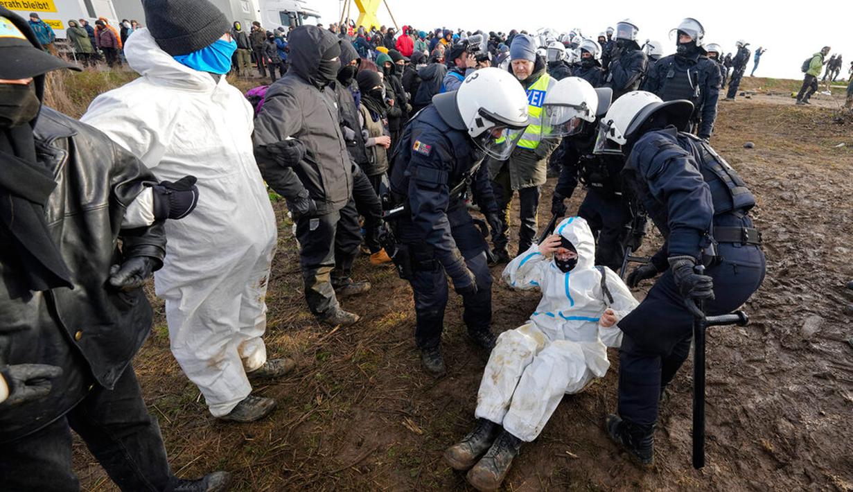 Polisi berbicara dengan seorang pengunjuk rasa untuk membersihkan jalan di Desa Luetzerath dekat Erkelenz, Jerman, 10 Januari 2023. Pengadilan Jerman menolak upaya terakhir para aktivis iklim untuk tinggal di desa yang ditinggalkan untuk perluasan tambang batu bara sehingga menjadi medan pertempuran antara pemerintah dan pencinta lingkungan. (AP Photo/Michael Probst)