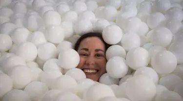 Seorang wanita tersenyum saat tenggelam dalam kolam bola putih di kantor SoHo, New York City, Selasa (25/8/2015). Tempat ini dibuat agar para karyawan dapat bermain dan dapat menhasilkan sesuatu yang kreatif. (REUTERS/Mike Segar)