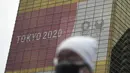 Seorang pria yang mengenakan masker berjalan di dekat spanduk Olimpiade dan Paralimpiade Tokyo 2020, di Tokyo, Jepang pada 27 Januari 2021. Olimpiade 2020 Tokyo yang ditunda terkait pandemi virus corona Covid-19 dijadwalkan ulang untuk diadakan pada musim panas ini.  (AP Photo/Eugene Hoshiko)