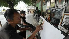 Seorang pelukis melukis di trotoar Kawasan Glodok, Jakarta, Selasa (15/5). Pelukis trotoar yang terhimpun dalam kelompok pelukis Kota ini menjual hasil lukisannya dan juga menawarkan jasa lukis potret. (Liputan6.com/Herman Zakharia)