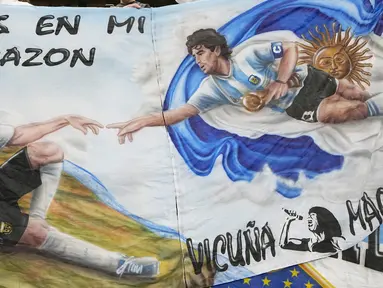 Lukisan bergambar Lionel Messi dan Diego Maradona dibawa oleh suporter saat menyaksikan laga antara Argentina melawan Meksiko. Lionel Messi kini bisa berbangga hati usai gol yang dicetak ke gawang Meksiko membuat dirinya sejajar dengan Diego Maradona. (AP Photo/Ariel Schalit)
