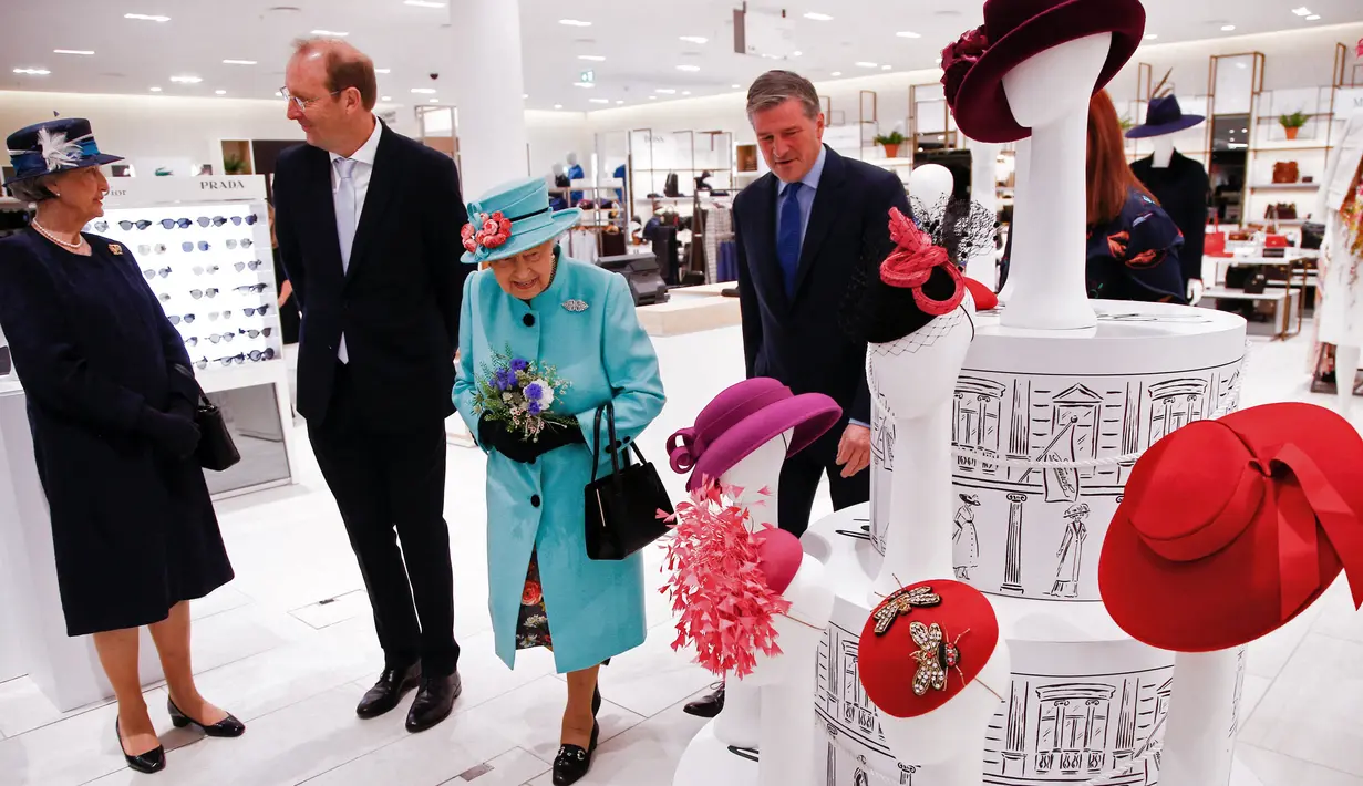 Ratu Elizabeth II melihat-lihat aksesoris topi di department store Fenwick saat mengunjungi pusat perbelanjaan Lexicon di Bracknell, London, Jumat (19/10). Ratu Elizabeth berjalan mengamati aksesoris sambil memegang buket bunga. (HENRY NICHOLLS/ POOL/AFP)