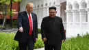 Momen ketika Presiden AS Donald Trump (kiri) dan Pemimpin Korea Utara Kim Jong-un berjalan di taman Hotel Capella, Pulau Sentosa, Singapura, Selasa (12/6). Kegiatan ini dilakukan saat istirahat pembicaraan antara AS-Korut. (Anthony Wallace/Pool/AFP)