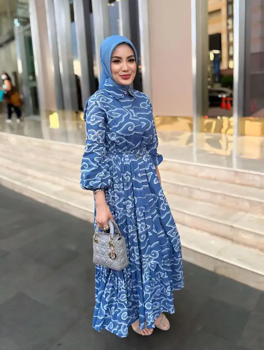 Kali ini, Nindy memancarkan pesona anggun dan feminim dalam balutan dress batik warna biru berpotongan a-line dari Batik Trusmi. Dress yang dipenuhi motif mega mendung itu ia padukan bersama hijab warna senada dan mini lady dior warna abu-abu seharga Rp95 jutaan, seperti yang dikutip dari Dior. [@nindyayunda]