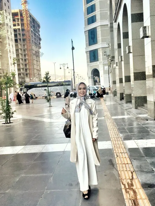 Begitu juga dengan Yuni Shara yang terlihat begitu memukau dalam balutan abaya putih serta coat. Ia menambahkan kerudung yang diikat sepurna dengan corak pastel. [Foto: Yuni Shara]