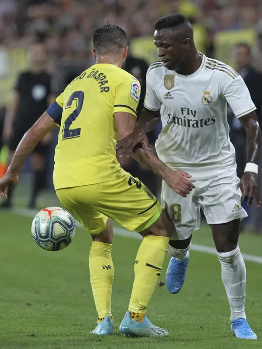 Penyerang Real Madrid, Vinicius Junior berusaha melewati pemain Villareal, Mario Gaspar  pada pertandingan La Liga Spanyol di stadion Ceramica (1/9/2019). Real Madrid bermain imbang 2-2 atas Villareal. (AP Photo/Alberto Saiz)