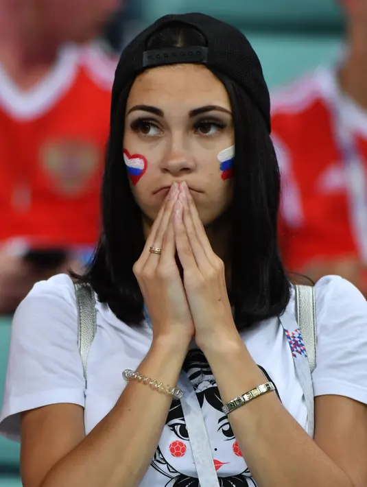 Seorang suporter Rusia terlihat kecewa setelah tim kesayangannya kalah dari Kroasia pada laga perempat final Piala Dunia 2018 di Stadion Olimpiade Fisht, Sabtu (7/7). Tuan rumah Rusia tumbang lewat adu penalti melawan Kroasia 3-4. (Nelson Almeida/AFP)