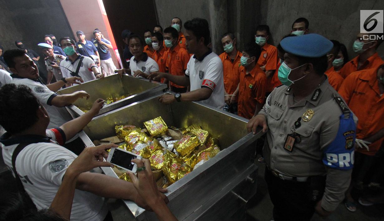 Petugas menunjukan barang bukti narkoba berserta tersangka di Bandara Soekarno-Hatta, Tangerang, Selasa (15/08). Selain itu juga 1,4 ton sabu dari Polda Metro Jaya dan 1,2 juta butir pil ekstasi dari Bareskrim Polri. (Liputan6.com/Helmi Afandi)