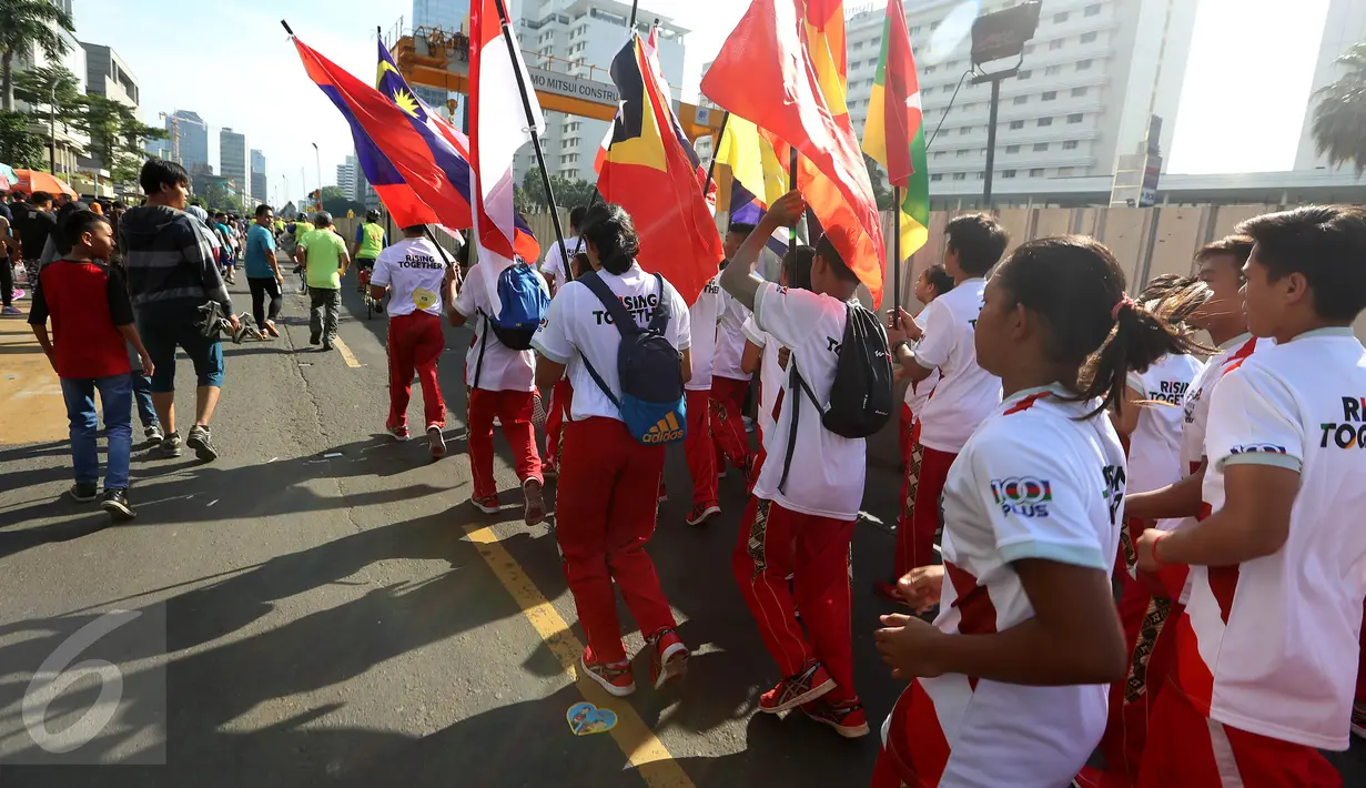 Sejumlah remaja membawa bendera negara-negara peserta Sea Games di Jakarta, Minggu (30/4). Kirab itu berlangsung guna menyambut Sea Games Kuala Lumpur 2017. (Liputan6.com/Johan Tallo)