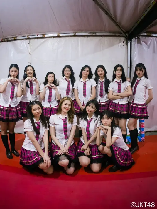Gaya kompak para member JKT48 mengenakan outfit anak sekolahan. Kemeja lengan pendek berwarna ptuih dipadukan dengan pleated skirt kotak-kotak bernuansa ungu dengan dasi pendeknya yang serasi. [Foto: Instagram/jkt48]