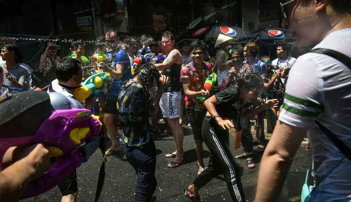 Orang-orang bersuka cita saling menyemprotkan air selama Festival Songkran di Silom Road, Bangkok, Jumat (13/4). Festival Songkran merupakan Tahun Baru Thailand dimulai dari tanggal 13 April sampai 15 April. (LILLIAN SUWANRUMPHA/AFP)