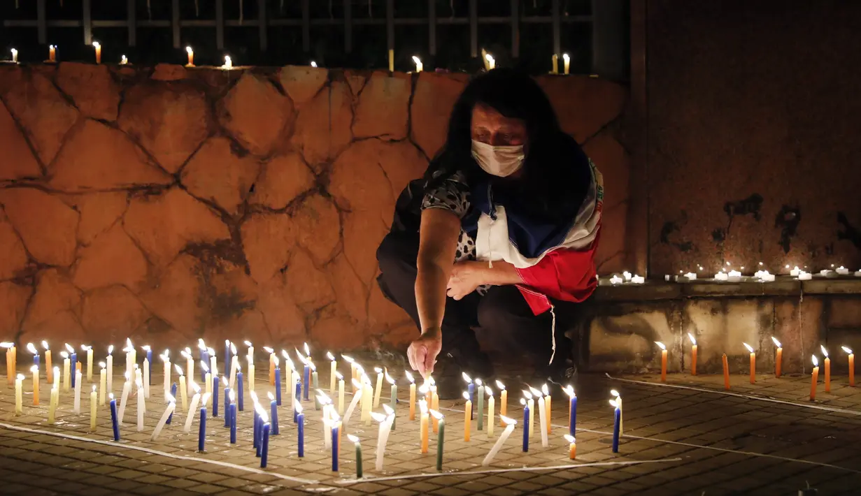 Emi Godoy menyalakan lilin untuk mengenang suaminya Sinforiano Roa yang meninggal karena komplikasi COVID-19, di depan Kementerian Kesehatan di Asuncion, Paraguay, Minggu (14/3/2021). Orang-orang menyalakan lilin untuk memberi penghormatan kepada 3.450 korban COVID-19. (AP Photo/Jorge Saenz)