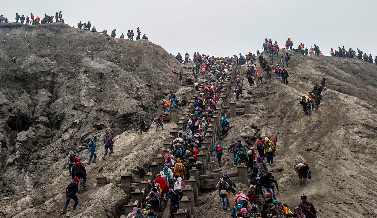 <p>Suku Tengger dan wisatawan mendaki tangga menuju puncak saat pelaksanaan ritual Yadnya Kasada di Gunung Bromo, Probolinggo, Jawa Timur, Kamis (18/7/2019). Bagi suku Tengger, Yadnya Kasada merupakan ritual adat yang wajib diselenggarakan setiap tahunnya tanpa ada kompromi. (JUNI KRISWANTO/AFP)</p>