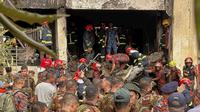 Petugas pemadam kebakaran memeriksa puing-puing pesawat latih milik Angkatan Udara Bangladesh yang jatuh di kompleks sekolah di Dhaka, Bangladesh, Senin (21/7/2025). (Dok. AP/Al-emrun Garjon)