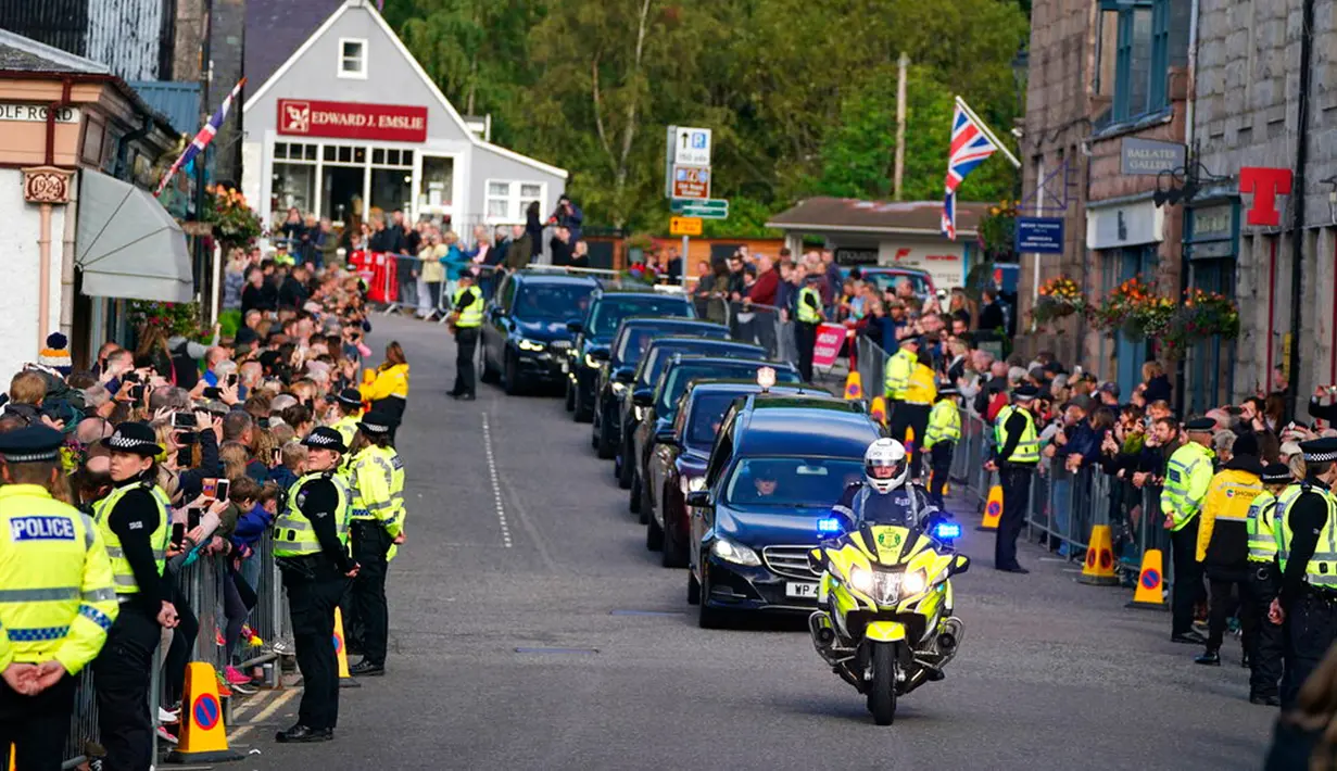 Warga berbaris saat mobil yang membawa peti berisi jenazah Ratu Elizabeth II melintas di Ballater, Skotlandia, Minggu (11/9/2022). Jenazah Ratu Elizabeth II diberangkatkan dari Kastil Balmoral ke Istana Holyroodhouse di Edinburgh sebelum nantinya akan dipindahkan ke London. (Andrew Milligan/PA via AP)