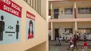 Murid-murid berjalan melewati poster dinding yang menyerukan protokol kesehatan Covid-19 di Sekolah Dasar Nalya pada hari pertama pembukaan kembali di Kampala, 10 Januari 2022. Sekolah-sekolah di Uganda dibuka kembali, mengakhiri penutupan sekolah terlama di dunia akibat COVID-19 (Badru KATUMBA/AFP)