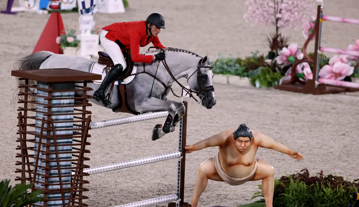 Gregory Wathelet dari Belgia mengendarai Nevados S melompat melewati patung sumo kecil di final individu lompat berkuda selama Olimpiade Tokyo 2020 di Equestrian Park di Tokyo (4/8/2021).
(AFP/Behrouz Mehri)